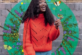A girl in an orange jumper surrounded by beautiful wildlife illustrations