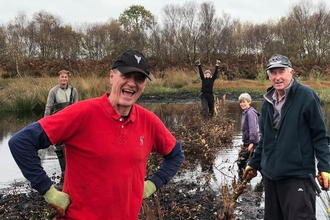 Group of 5 volunteers building a dead hedge in an area of open water on Little Woolden Moss