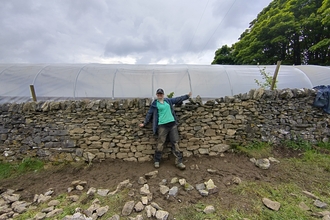 A woman standing in front of a dry stone wall
