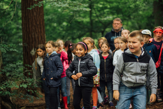 A group of school children smiling and laughing in the woods