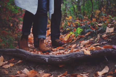 A couple walking through autumn leaves in a woodland