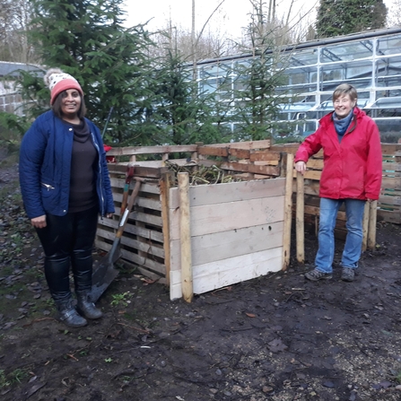 2 people with a new compost bay outside a greenhouse
