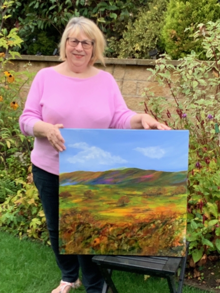 Artist, Carolyn Dutton, and her winning entry for the 'wild scenery' category which depicts a summery hill landscape