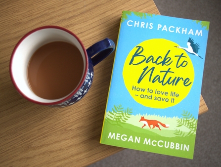 The book Back to Nature by Chris Packham and Megan McCubbin, sits on a table next to a cup of tea.