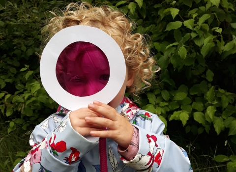 A little girl with a magnifying glass she made at Nature Tots at Heysham Nature Reserve