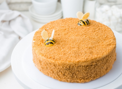 A cake covered in crumble topping with icing sugar bees on top
