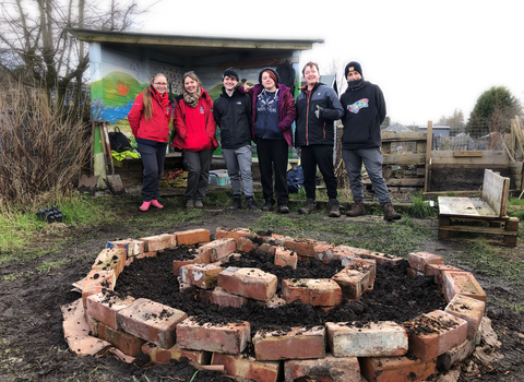 A group of people by a herb spiral on an allotment