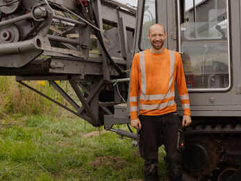 A man standing in from of a harvesting machine