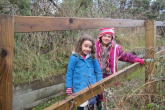 Children standing on a wooden bridge amongst nature at Heysham Nature Reserve