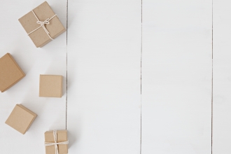 Presents wrapped in brown paper and string on white floorboards