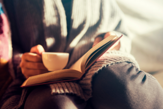A person with a book and coffee in their lap