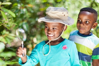 Two children searching for minibeasts with magnifying glass