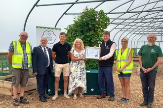 Certificate being handed over from Craig Bennet to Blackburn farm owners