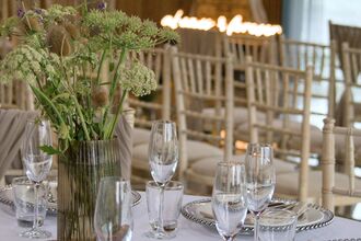 A close up of a table set ready for a wedding with rows of seats in the background
