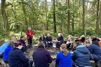 Forest School trainees doing woodland crafts around the fire circle