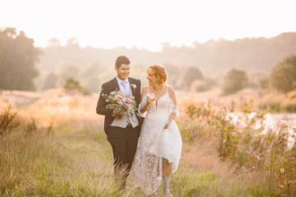 A bride and groom walk along the riverside at Brockholes