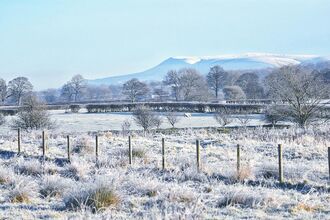A view across snowy fields to Pendle Hill seen from Brockholes
