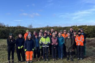 Image of group of volunteers from APEM Limited stood on Freshfield Dune Heath with blue sky