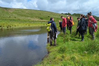Members of the GM Land Managers' Group stood next to a pond