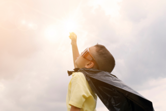 Child with a cape on in a superhero pose