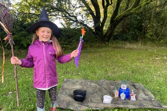 Child in witches hat with a wand and broom