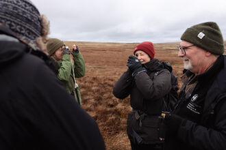 A group of people looking through a lens at moss