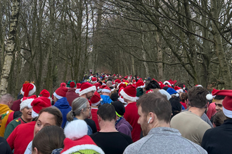 A group of people in the woods wearing santa hats ready to do a run in the park