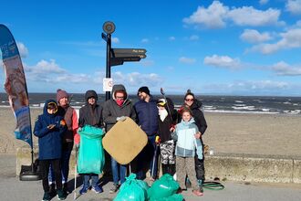 A group of people standing by the beach in Fleetwood with rubbish collected off the beach