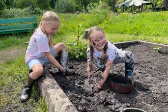 Two children having fun playing in the mud pit at The Hive