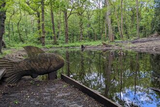Wooden fish sculpture overlooking a restored pond