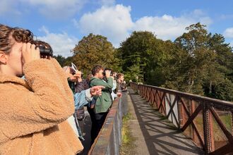 A group of people in a line birdwatching