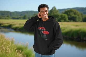 A man wearing a mushroom hoodie in front of a river