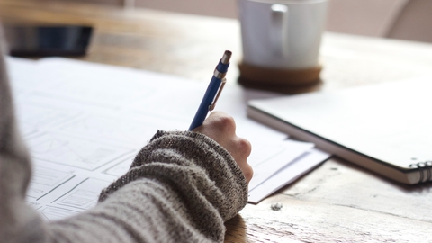 A woman writing a Will at a wooden table