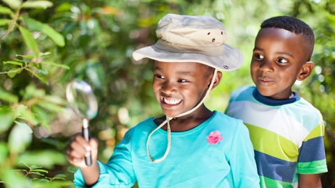 Two children searching for minibeasts with magnifying glass