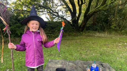 Child in witches hat with a wand and broom
