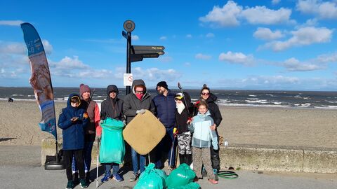 A group of people standing by the beach in Fleetwood with rubbish collected off the beach
