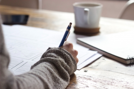 A woman writing a Will at a wooden table