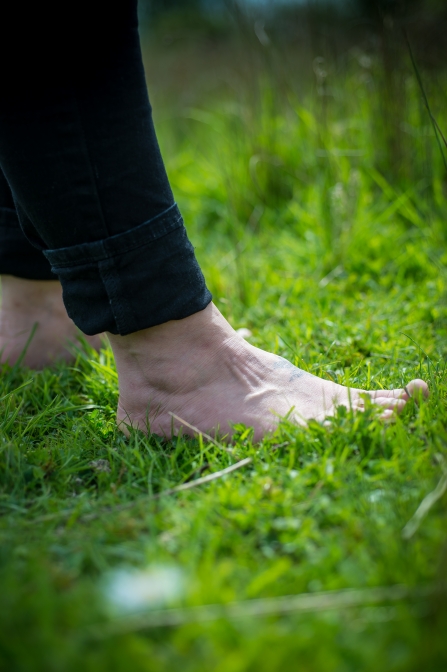 A person standing barefoot on lush green grass