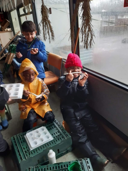 A Forest School class taking part in crafts on a rainy day