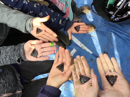 Stone age workshop participants showing off arrowheads they have made from flint