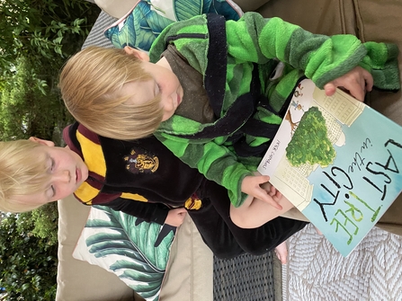 Two children in nightgowns reading an environmental book outdoors