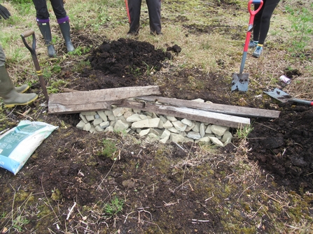 Trench filled with rocks and wooden batons to create the hibernaculum