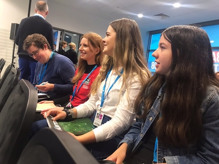 Youth Council members sitting in a seminar at the Conservative Party Conference and smiling