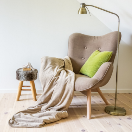 An empty armchair, lamp and stool 