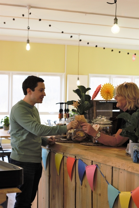 A member of staff handing food over the counter to a customer in the Mere Sands Wood cafe