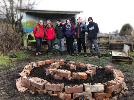 A group of people by a herb spiral on an allotment