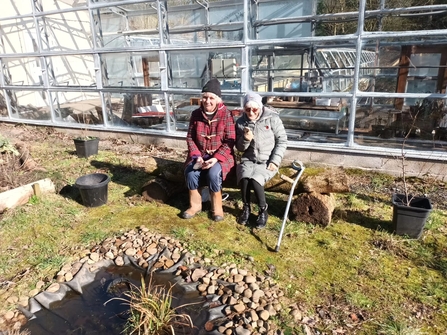 Hazel and Dilys sitting in the forest garden in the cool spring sunshine