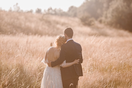 A bride and groom looking across a meadow at Brockholes