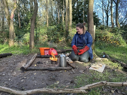 forest school trainee making a fire in a kelly kettle