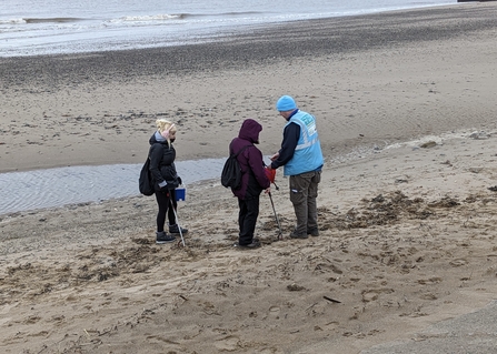3 people standing on a beach
